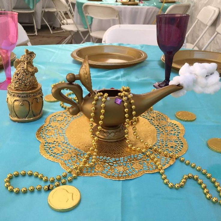 a teapot on a table decorated with gold beads and other decorations for a party