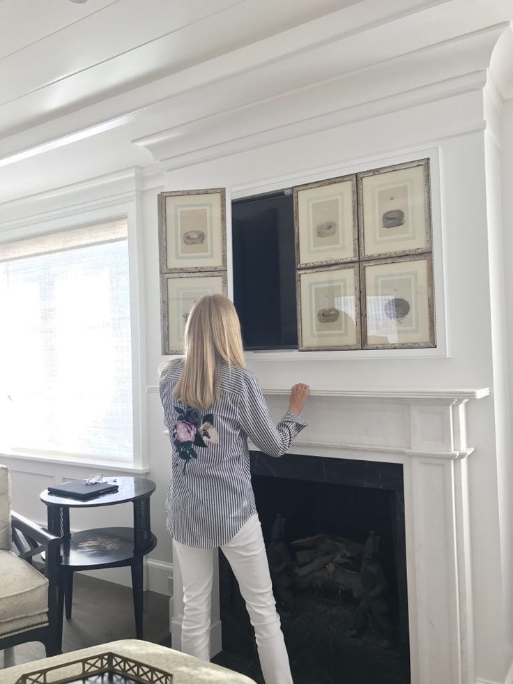 a woman standing in front of a fire place with her hands on the fireplace mantel