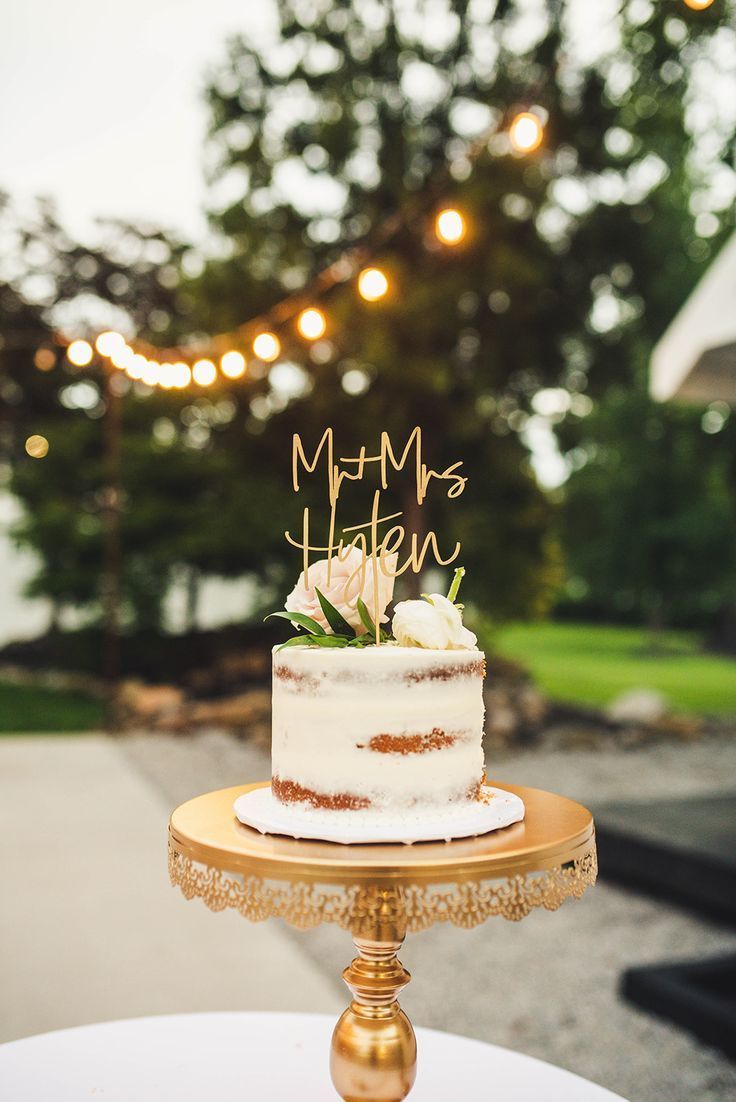 a wedding cake sitting on top of a white table next to a string of lights