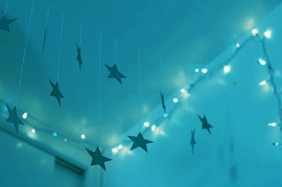 stars hanging from the ceiling in a room with blue walls and white lights on it