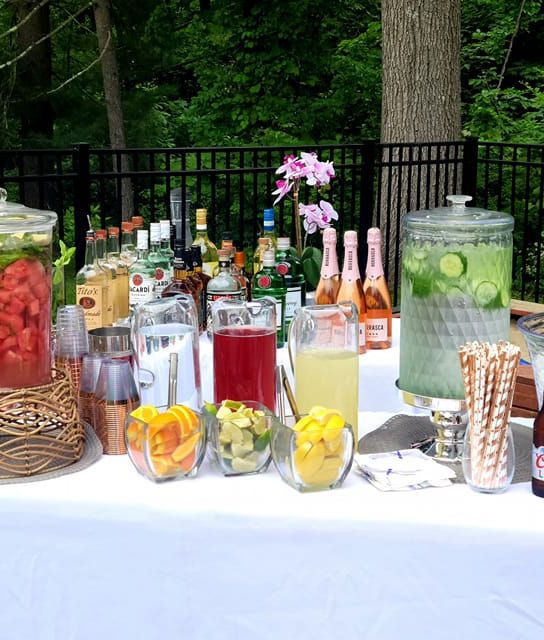 a table topped with lots of different types of drinks next to bottles and glasses filled with liquid