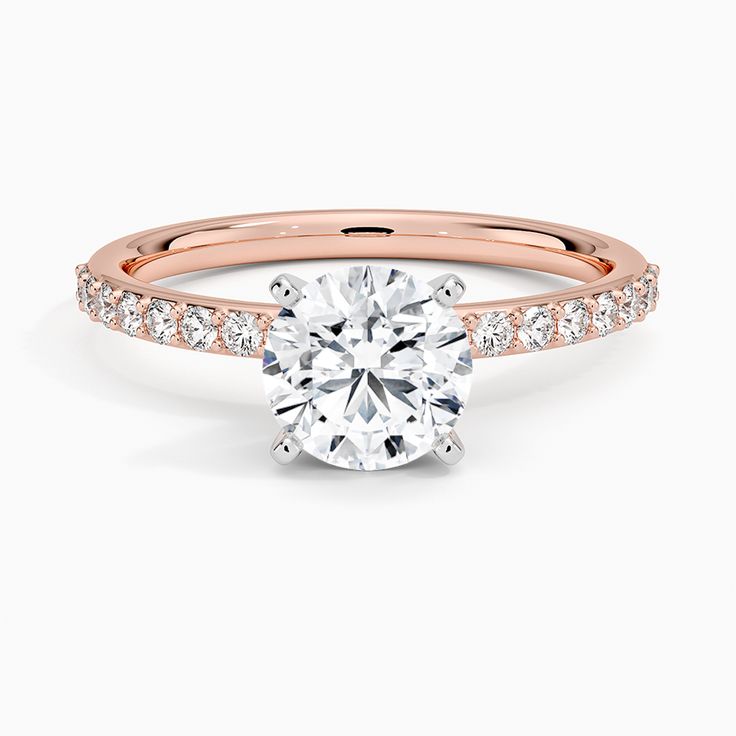 a rose gold engagement ring with diamonds on the band and a round cut diamond in the center