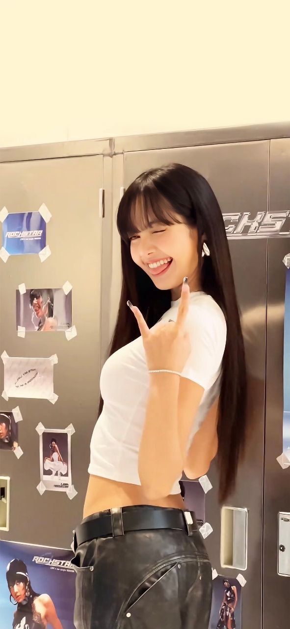 a woman standing in front of a refrigerator giving the peace sign