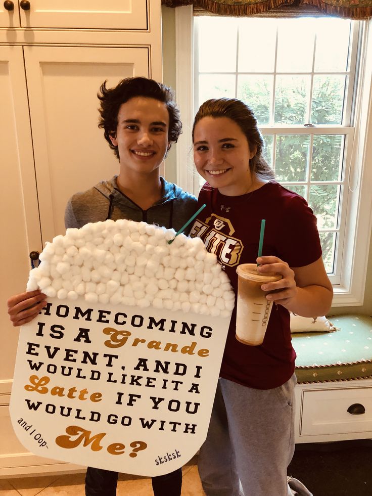 two people standing in front of a window holding a sign