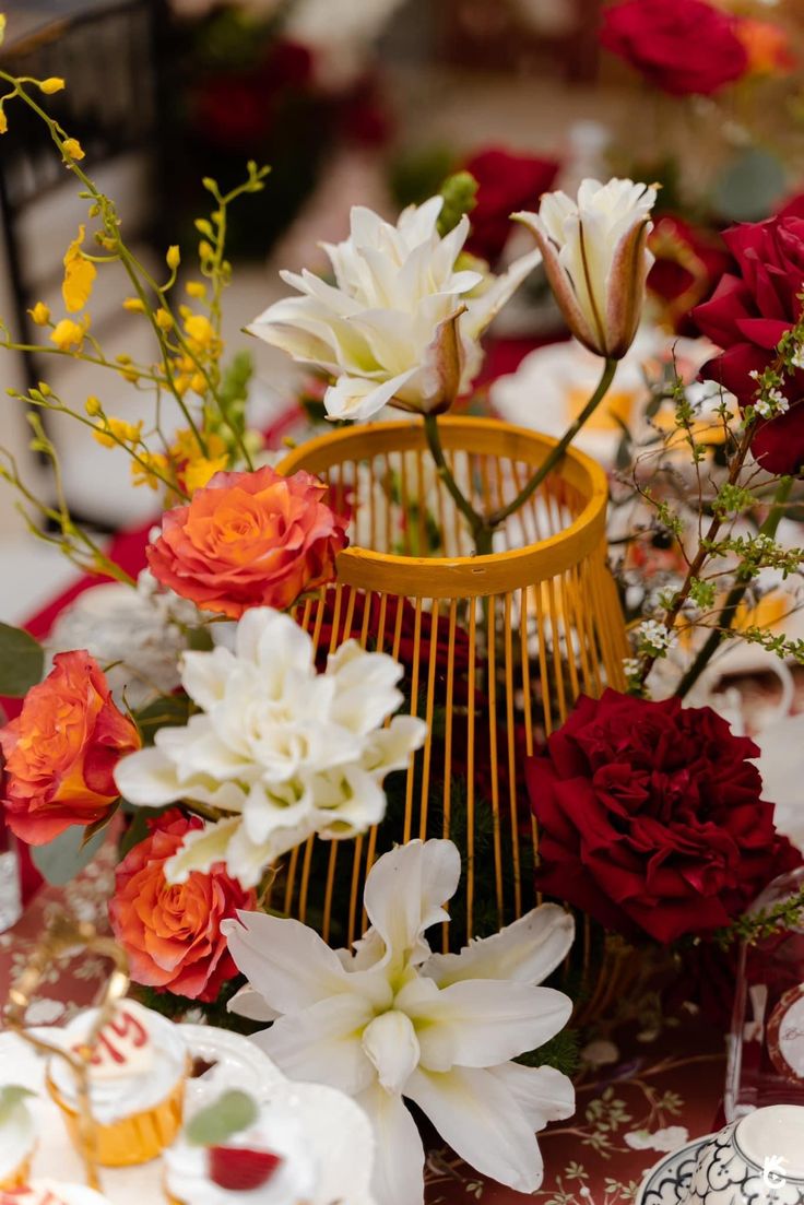 an arrangement of flowers in a vase on a table with other plates and utensils