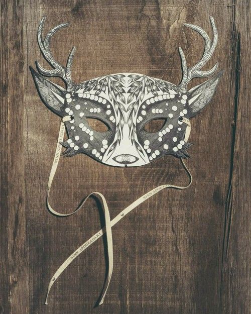 a mask with antlers on it sitting on top of a wooden table