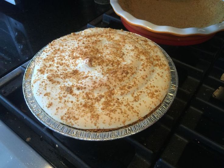 a pie sitting on top of an oven next to a pan filled with cake batter