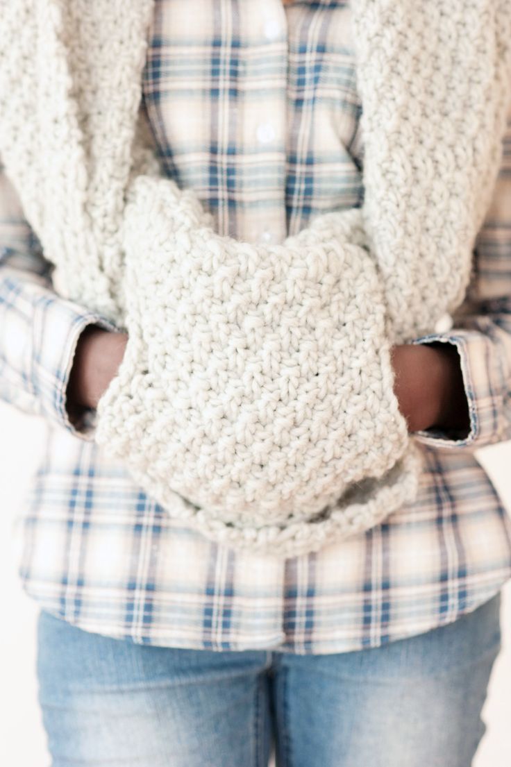 a woman is wearing a crocheted scarf around her neck and holding it in her hands