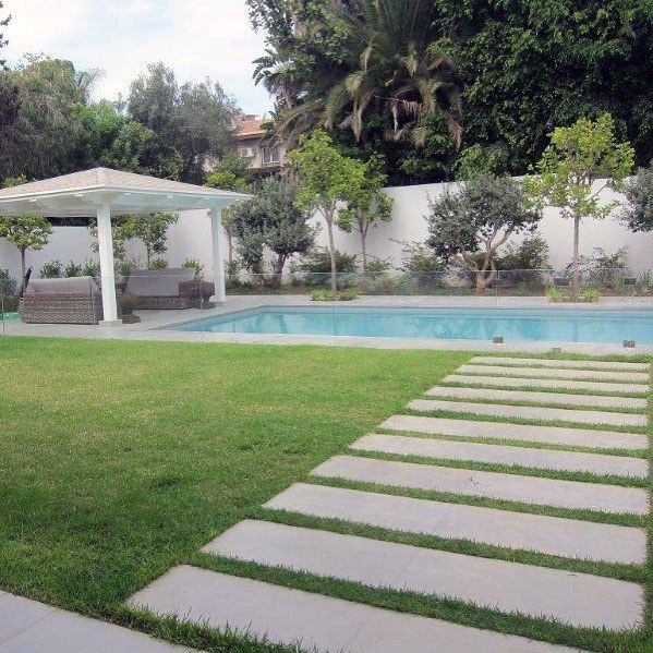 a large backyard with a pool and grass area next to the yard, covered by a white pergolated gazebo