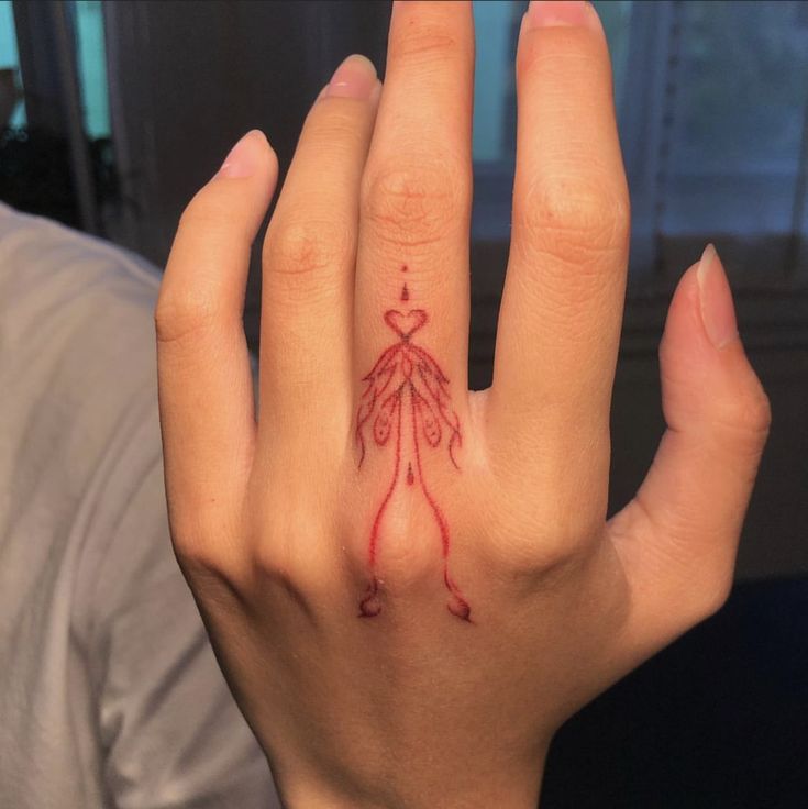 a woman's hand with a red tattoo on her left thumb and the word love written in it