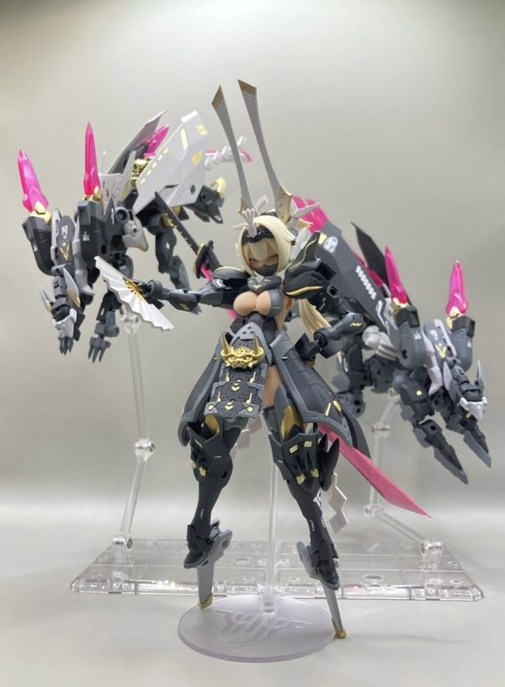 an action figure is posed on a clear base with pink and white accents, holding two swords