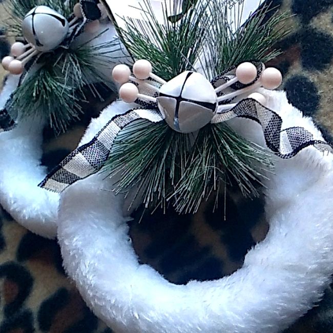 two christmas wreaths are on top of a leopard print rug, one is decorated with white and black ribbon