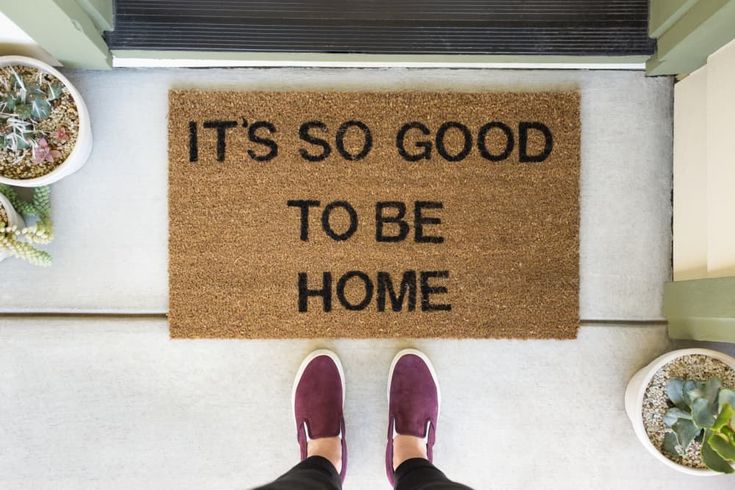 someone standing in front of a door mat that says it's so good to be home