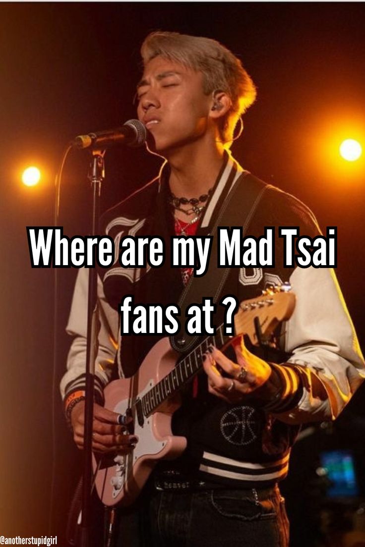 a man holding a guitar and singing into a microphone with the words where are my mad tsai fans at?