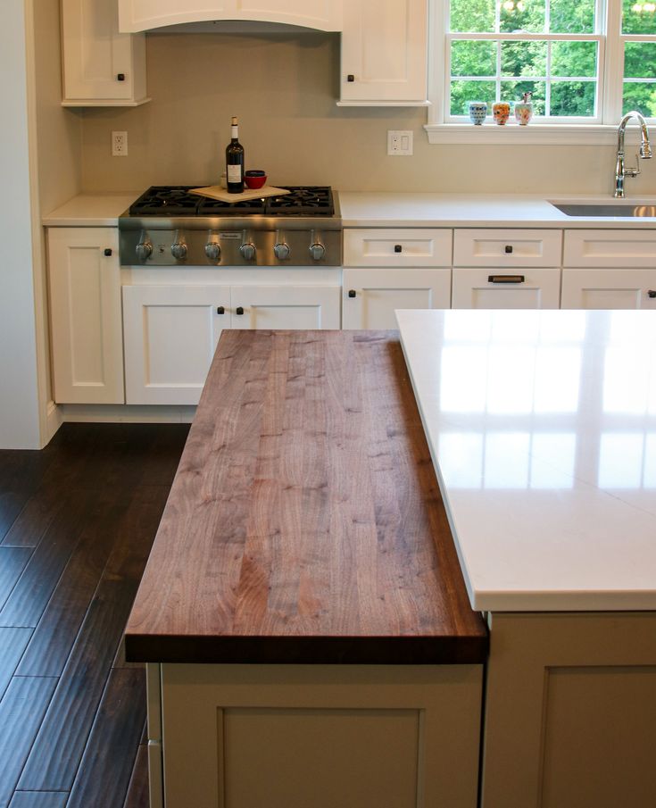 a kitchen with white cabinets and wood counter tops in front of a stove top oven