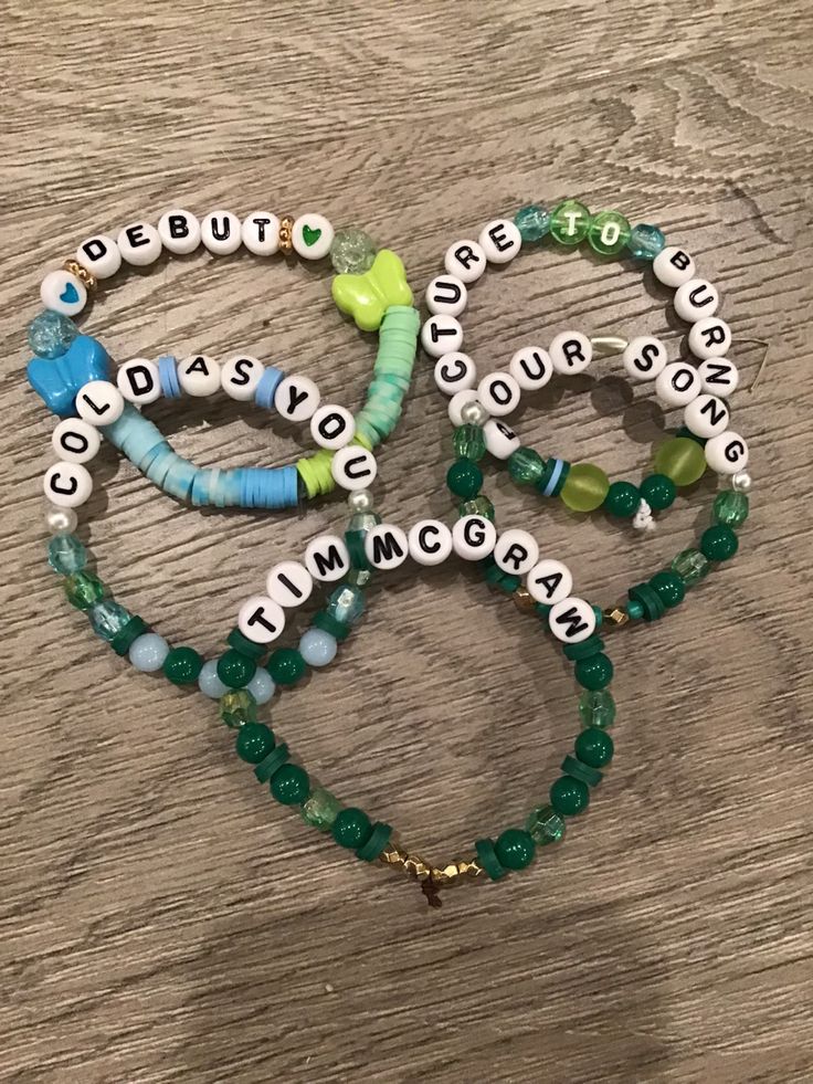 three bracelets with words on them sitting on top of a wooden table