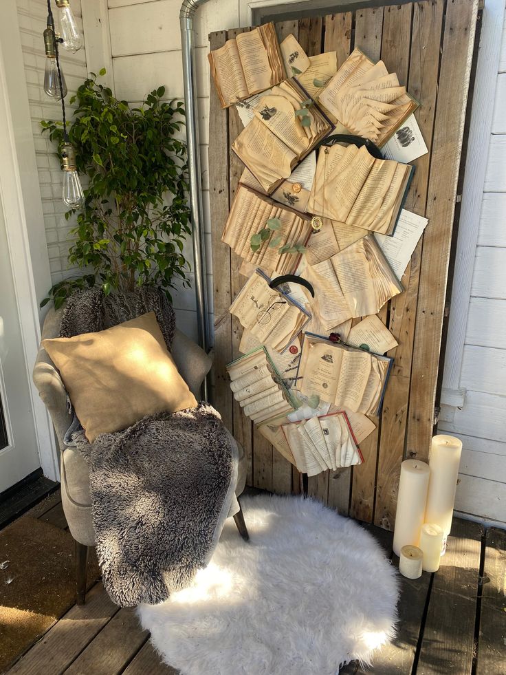 a pile of books sitting on top of a wooden floor next to a chair and potted plant