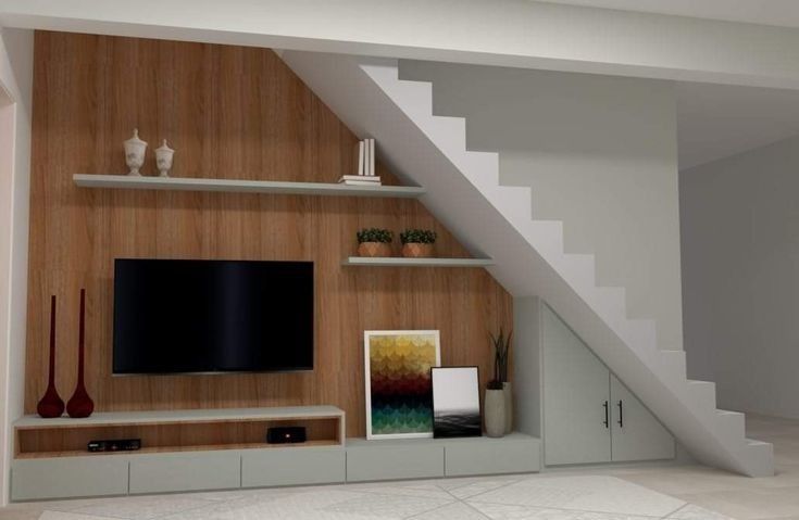 an entertainment center under the stairs in a room with wood paneling and white walls