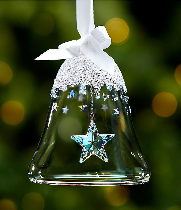 a glass bell ornament with a star hanging from it's side and a white bow on top