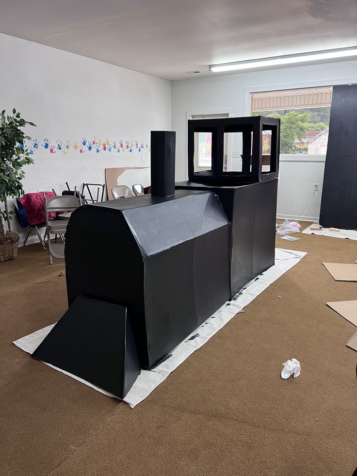 an empty room with black furniture in the middle and cardboard on the floor around it