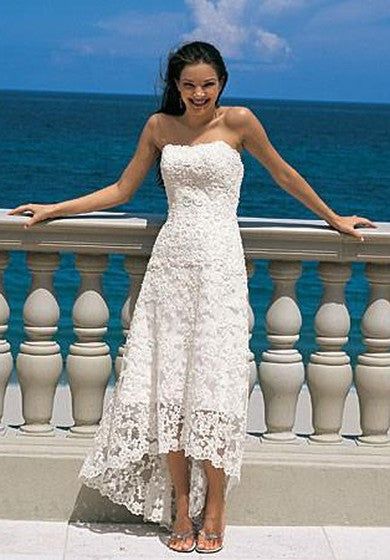 a woman in a white dress standing on a balcony next to the ocean with her arms outstretched