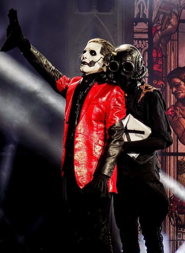 two people dressed in costumes standing next to each other with their hands up and one person wearing a mask