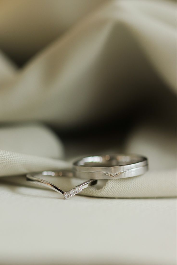 two wedding rings sitting on top of a white cloth