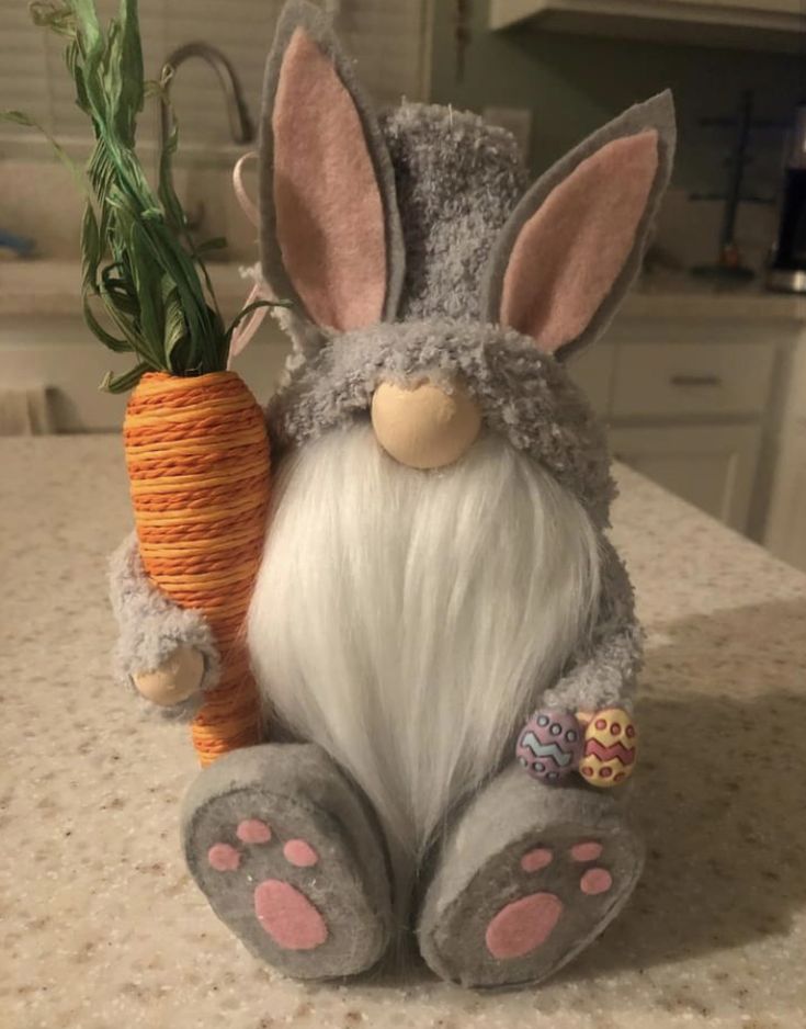 a stuffed rabbit holding a carrot on top of a counter