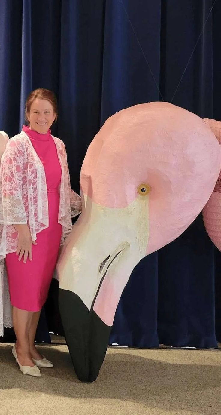 a woman standing next to a giant pink flamingo balloon