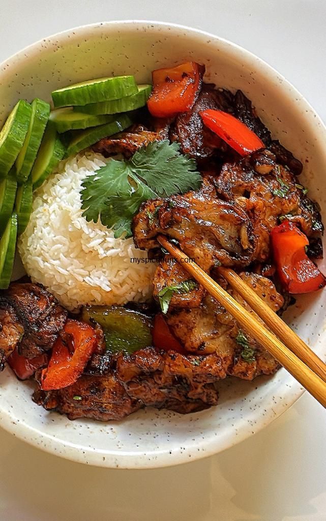 a bowl filled with rice, meat and veggies next to chopsticks