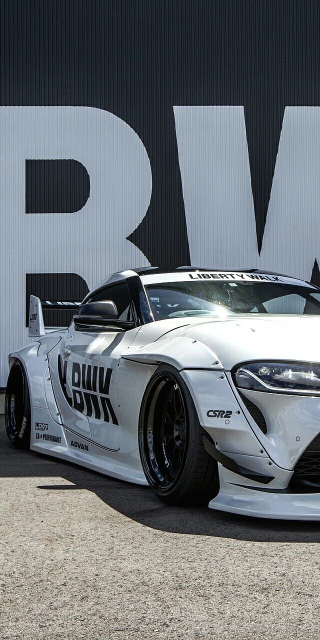 a white sports car is parked in front of a large sign with the word bmw on it