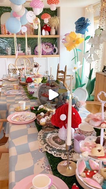 a long table with many plates and cups on it, decorated with balloons in the background