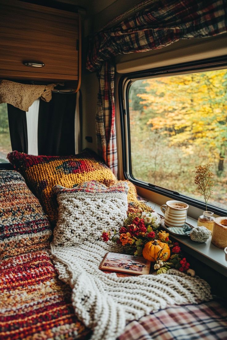 a bed in a camper with pillows and blankets on it next to a window