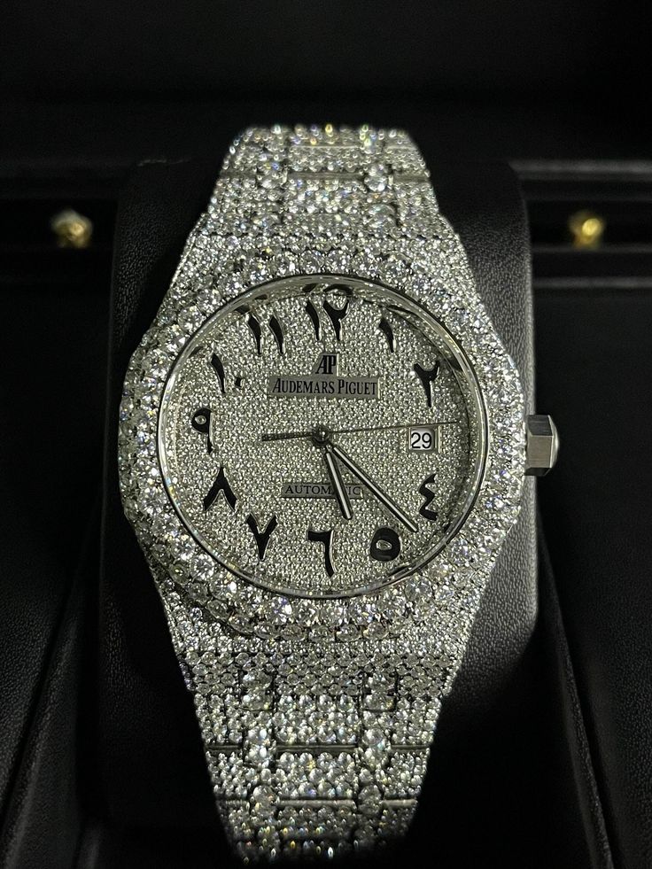 This is a stunning luxury wristwatch from the brand Audemars Piguet. The watch features a round white dial with Arabic numeral indices and a 12-hour analog display. The case is made of stainless steel and has a size of 41mm. The watch is water-resistant up to 30m (3 ATM) and comes with its original box and papers.The watch has a mechanical (automatic) movement and a white stainless steel band that complements the white case. The watch is made with the highest quality moissanite stones and has 30 carats and about 2800 stones. It is a customized model of the Audemars Piguet Royal Oak, and has a unique appeal that makes it a must-have for watch enthusiasts. This watch is a perfect accessory for men who want to add a touch of luxury to their style. Ap Watch, Hand Watches, Rolex Diamond Watch, Men's Watch Accessories, Hip Hop Watches, Hip Hop Trends, Diamond Watches, Jewelry Drawer, Men's Vintage Style