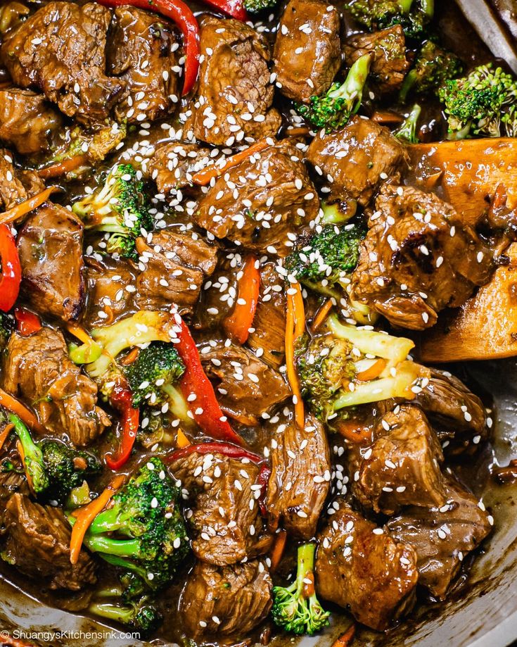 beef and broccoli stir - fry with sesame seeds in a skillet, ready to be eaten