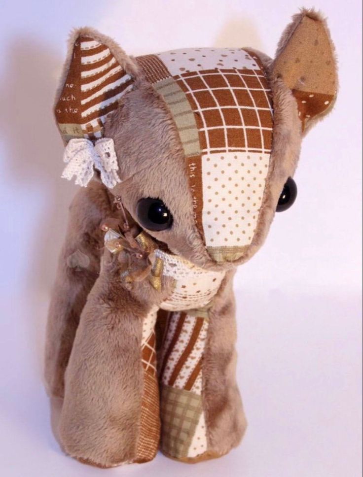 a stuffed animal is wearing a brown and white checkered dress with a bow on it's head