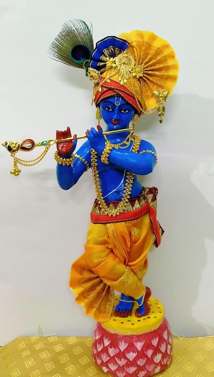 a statue of a hindu god with a flute in his hand, on a yellow table