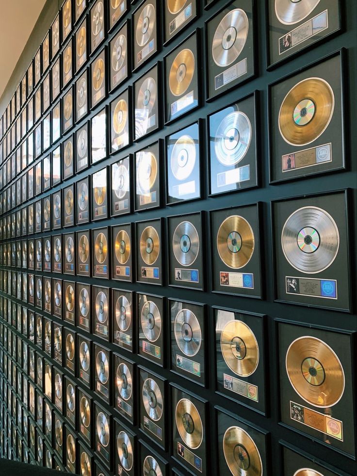 there are many cds on the wall and one is in front of them with gold discs all over it