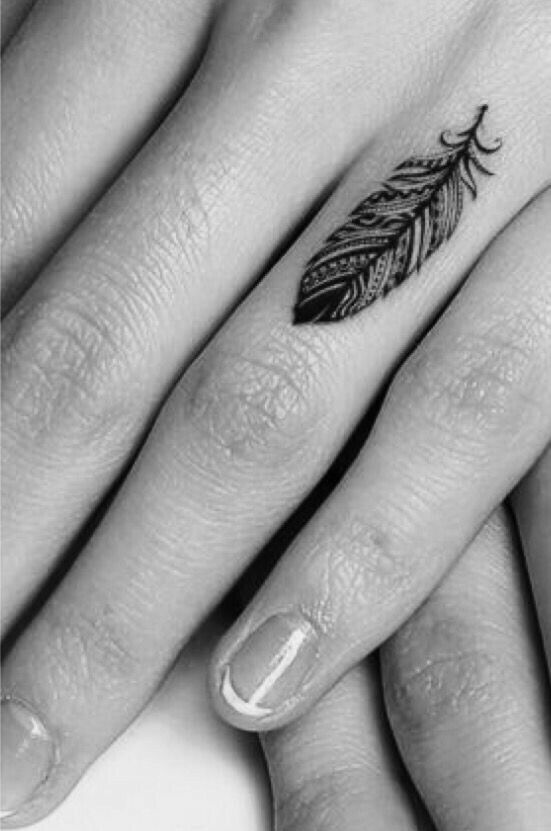 two hands holding each other with tattoos on their fingers and one has a feather tattoo on it