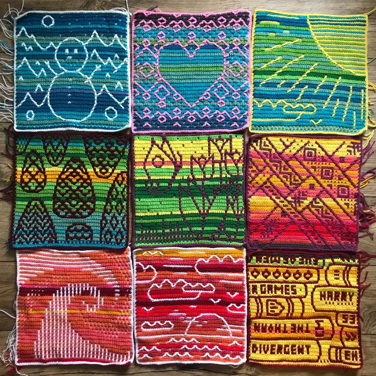 several colorful crocheted squares are arranged on a wooden surface, with yarn in the middle