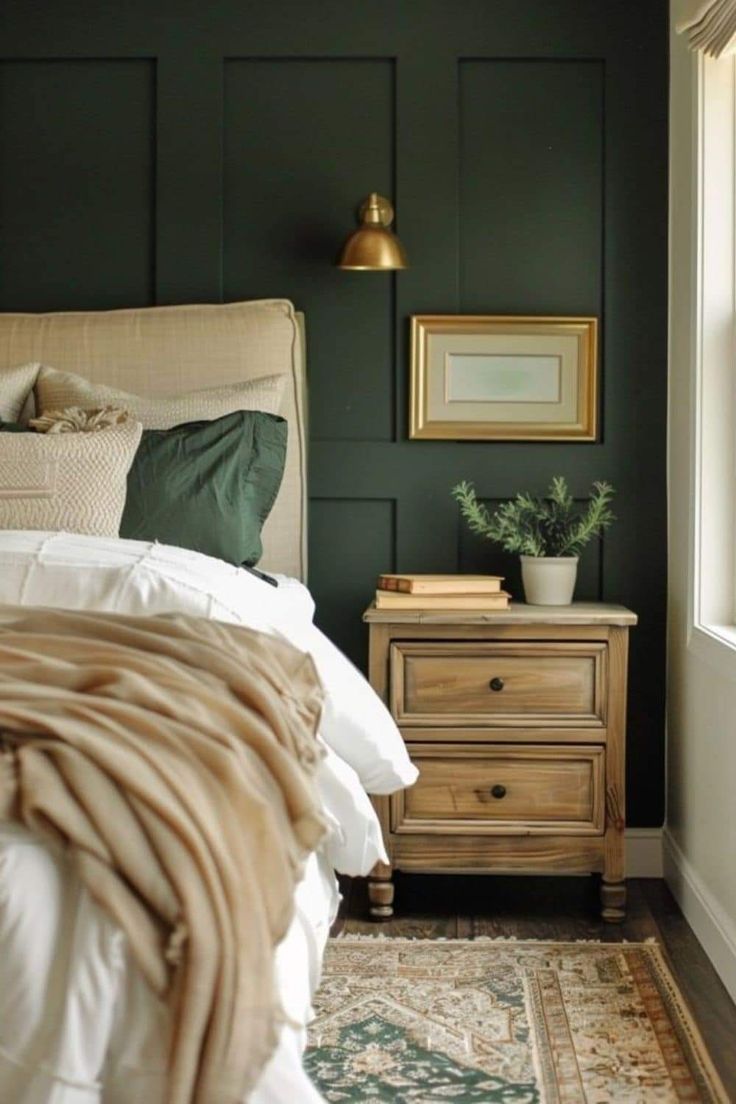 a bedroom with dark green walls and white bedding, gold framed pictures on the wall