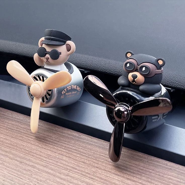 two toy bears sitting on top of an airplane