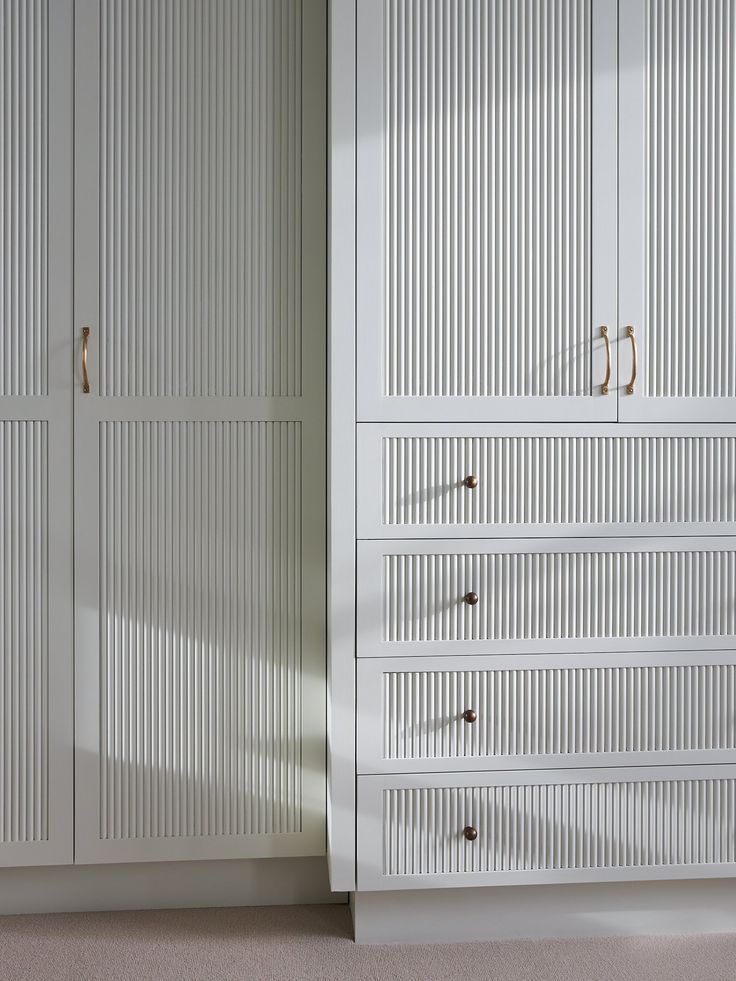 a white closet with two doors and drawers next to it's carpeted floor