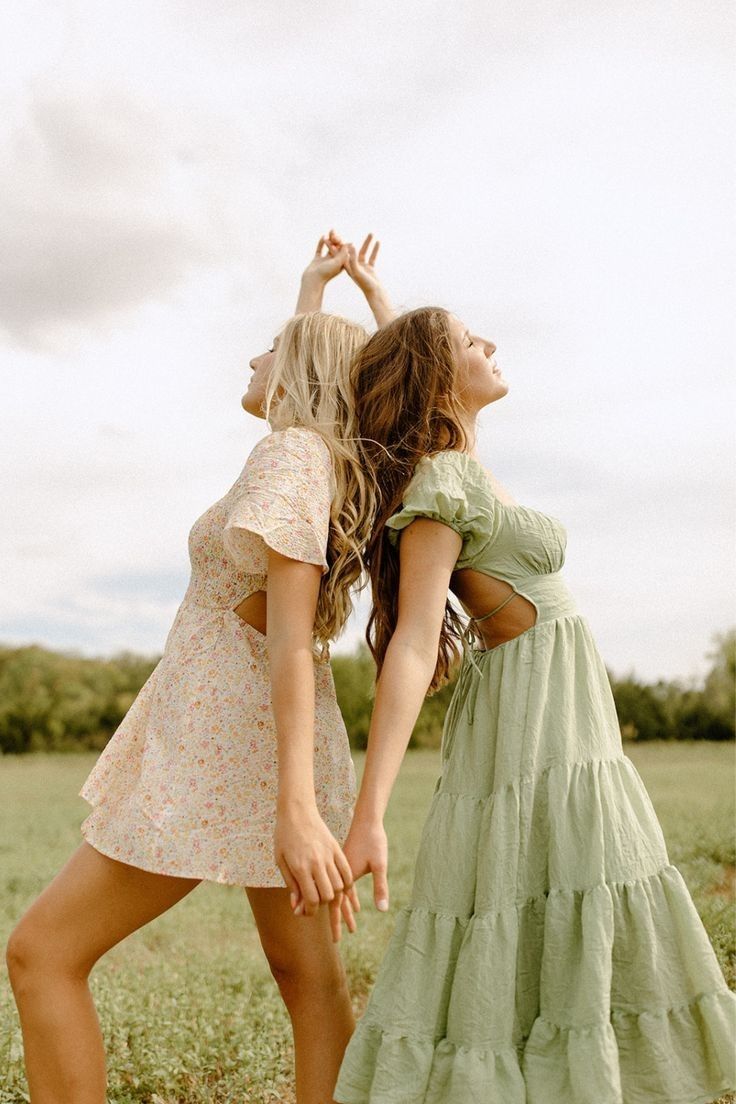 two young women are dancing in a field