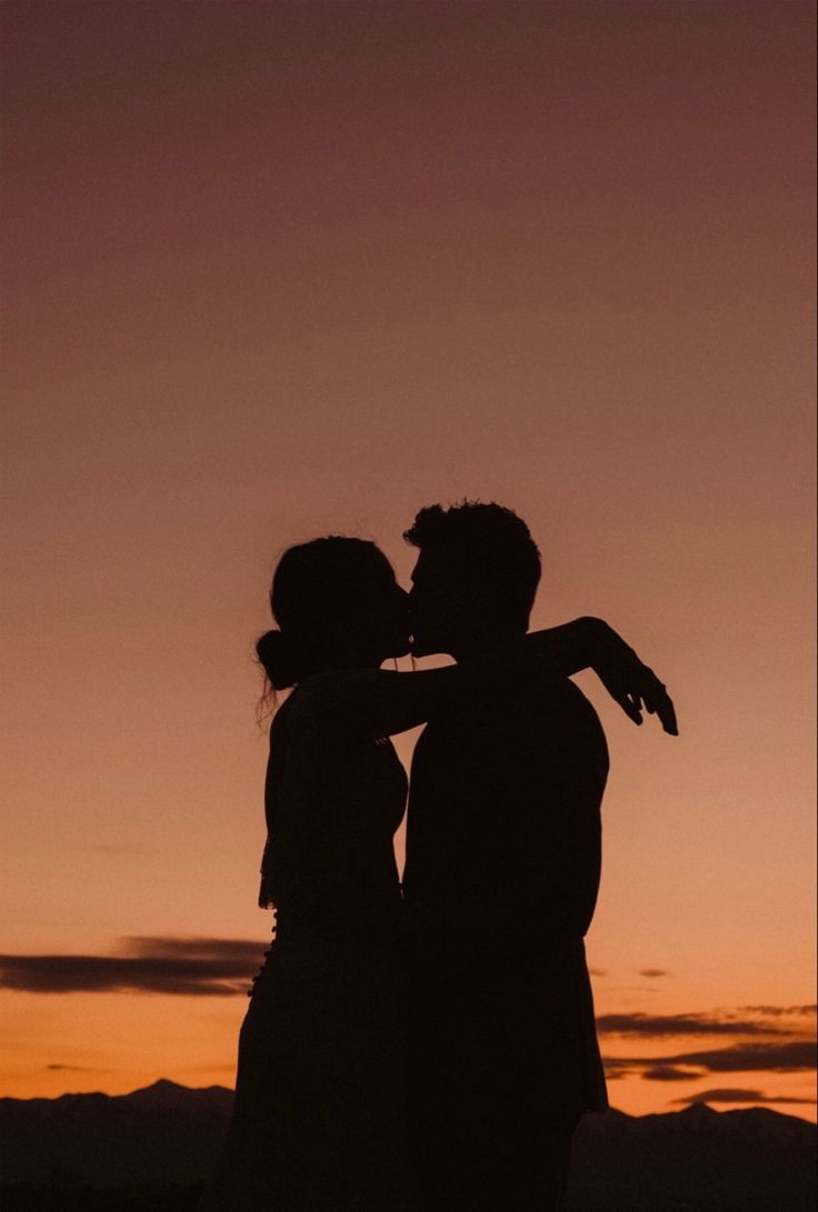 two people standing next to each other at sunset