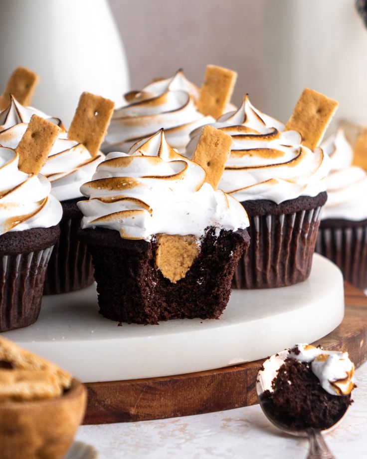 chocolate cupcakes with white frosting and graham crackers on top