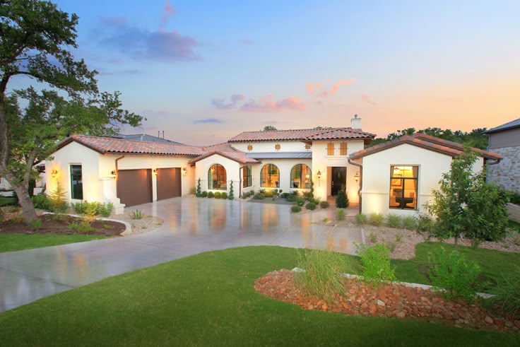 a large white house with lots of windows and lights on it's front yard