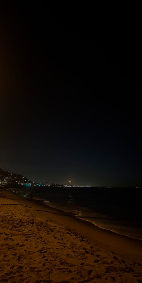 the beach is lit up at night and there are no people on it or in the water