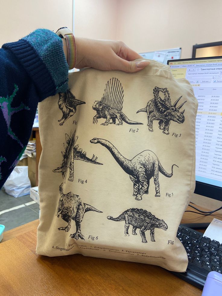 a bag with dinosaurs printed on it sitting in front of a computer