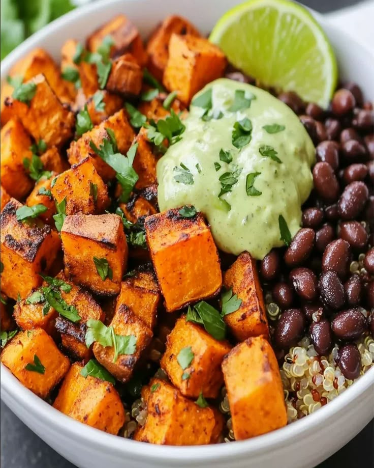 a bowl filled with black beans, sweet potatoes and guacamole on top